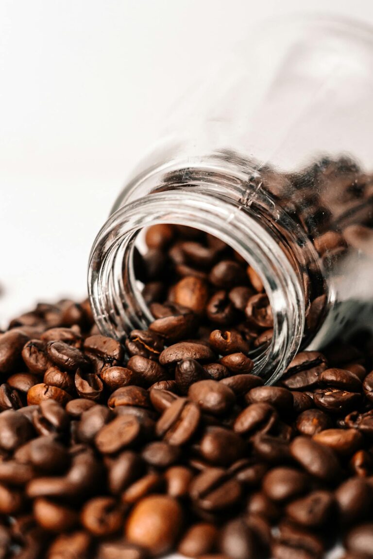 Aromatic coffee beans spilling from a glass jar, perfect for a cafe theme.