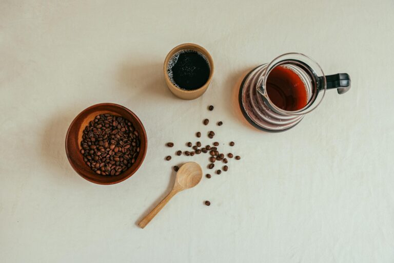 Top-down view of coffee beans, a mug, and a drip coffee pot. Warm, rustic style.